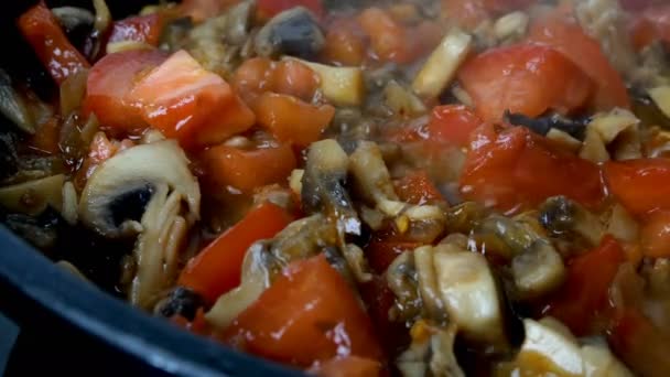 Grzyby drobno posiekane i pomidory smażone są na patelni we wrzącej oliwie z warzyw lub oliwy z oliwek. Kuchnia domowa. Dolly postrzelona. Zbliżenie. — Wideo stockowe