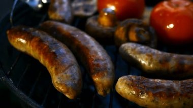 Izgarada ya da ızgarada pişirilmiş yağlı bavyera sosisi. Sebzeli domates ve mantarlı. Yakın plan..