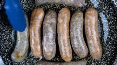 Birkaç lezzetli Bavyera et sosisi. Kızartma tavasında kabuklu sosisler ve sebze yağıyla mutfak maşası. Üst Manzara. Yakın plan..