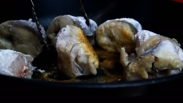 Witte zeevisheek koken, in stukken snijden in een koekenpan. Gebakken heek of pollak met gouden korst voorbereiding op de huishoudelijke keuken. Gefrituurde vis recept. Selectieve focus. Close-up. — Stockvideo