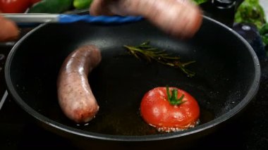 Bavarian sausages with tomato and sprig of rosemary are fried in frying pan and fried eggs with flowing yolk. English or German, European or American breakfast. Close-up.