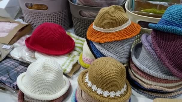 Куча различных типов летних шляп отображается на прилавке магазина. Текстильная мода ретро одежда. Большой ассортимент товаров ручной работы. Крупный план. — стоковое видео