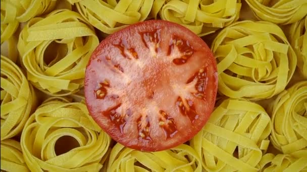 Veel droge tagliatelle pasta, gegarneerd met gesneden tomaat in het midden van de cirkel, draaien met de klok mee. — Stockvideo