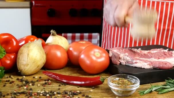 Chef bate em fatias cruas frescas carne de porco com martelo de cozinha antes de cozinhar na tábua de corte. Preparação esmagando costeletas de porco de bife. Polvilhe com especiarias. Legumes diferentes. Dolly atirou. — Vídeo de Stock