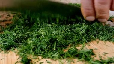 Taze yeşil dereotu mutfak bıçağıyla kesmek, yeşilliği sağlıklı vejetaryen ya da vejetaryen gıda hazırlıkları için vitaminle hazırlamak. Seçici odaklanma. Yakın plan..