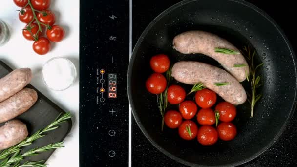 Embutidos bavarianos blancos grasos con tomate y ramita de romero frito en sartén sobre estufa eléctrica. Desayuno inglés o alemán, europeo o americano. Vista superior. Comida de arriba hacia abajo. Primer plano. — Vídeos de Stock