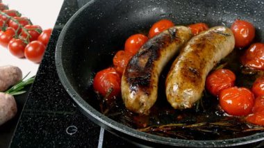 Domatesli ve biberiyeli yağlı beyaz bavyera sosisleri elektrikli sobada kızartma tavasında kızartılıyor. İngiliz ya da Alman, Avrupa ya da Amerikan kahvaltısı. Yakın plan..