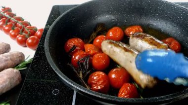 Domatesli ve biberiyeli yağlı beyaz bavyera sosisleri elektrikli sobada kızartma tavasında kızartılıyor. İngiliz ya da Alman, Avrupa ya da Amerikan kahvaltısı. Yakın plan..