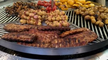 Hazırlık kuzu ya da domuz pirzolası, patates, mantar, sokak pazarında dönen ızgarada dolmalık biber. Sokak yemekleri festivali. Yakın plan..