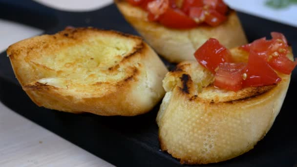 Σεφ που ετοιμάζει κλασική ιταλική ή μεσογειακή μπρουσκέτα με ψητή μπαγκέτα και πασπαλισμένη με ντομάτα. Διακοσμημένο με φύλλα βασιλικού. Υγιεινό χορτοφαγικό σνακ. Κοντινό πλάνο. — Αρχείο Βίντεο