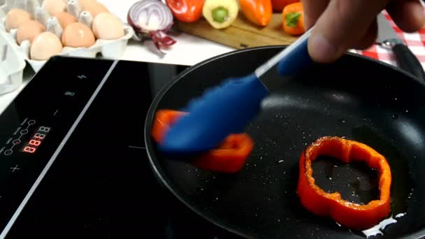 Preparación de huevos fritos en anillo de pimiento y ramitas de romero y tomillo en la sartén en la estufa eléctrica. Alimento vegetariano nutritivo en su cocina doméstica. Plano medio o primer plano. — Vídeos de Stock