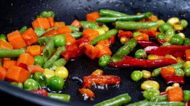 Geleneksel Meksika sebzeleri kızartılıyor. Mısır, kırmızı dolma biber, yeşil fasulye, yeşil bezelye ve tavada havuç karışımı. Lezzetli vejetaryen ya da vegan yemek tarifi. Ev mutfağı. Yakın plan..