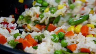 Geleneksel Meksika sebzelerini kızartarak mısır, kırmızı dolma biber, yeşil fasulye, yeşil bezelye, havuç ve pilavı kızartma tavasında karıştır. Lezzetli vejetaryen ya da vegan yemek tarifi. Ev mutfağı..