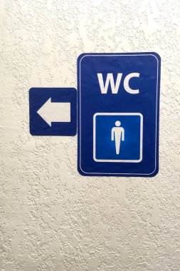 Ok, umumi erkekler tuvaletinin mavi işaretinde işaret, sıva kaplı duvarda işaret. Tuvalet tabelası. Tuvalet konsepti. Yatay çekim. Uzayı kopyala Yakın plan..