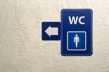 Ok, umumi erkekler tuvaletinin mavi işaretinde işaret, sıva kaplı duvarda işaret. Tuvalet tabelası. Tuvalet konsepti. Yatay çekim. Uzayı kopyala Yakın plan..