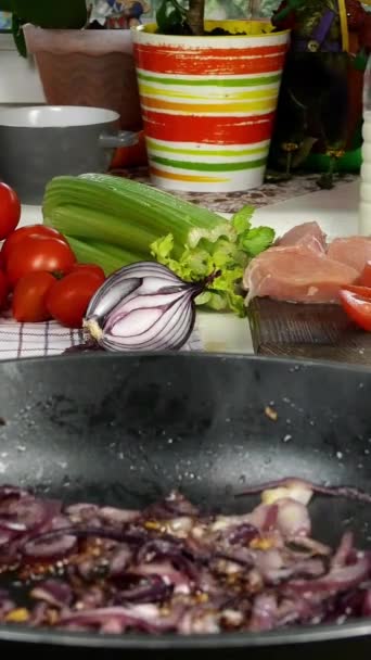 Tafel in de keuken. Voorbereiding van mediterraan voedsel. Braadpan gesneden ui. Chef deed tomaten in blik voor het maken van saus met kippenvlees, ui, selderij. Verticaal formaat. Close-up. — Stockvideo