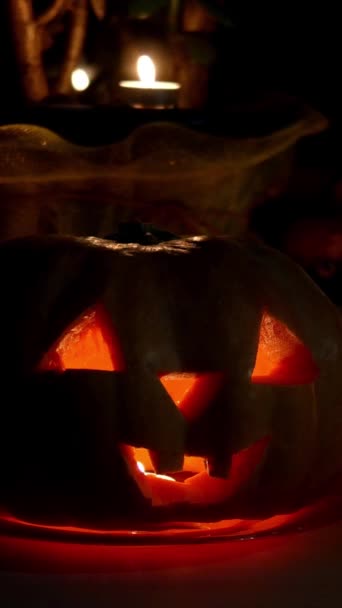 Decorazione domestica con spettrale brilla Halloween zucca testa Jack Lanterna viso e candela accesa. Occhi scolpiti, bocca. Video verticale. Simbolo tradizionale di Halloween. — Video Stock