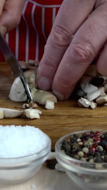 Chef ciuperci de tăiere cu cuțit de bucătărie mare ascuțit pe bord de tăiere din lemn pentru prepararea alimentelor. Conceptul de alimentație sănătoasă. Video vertical . — Videoclip de stoc