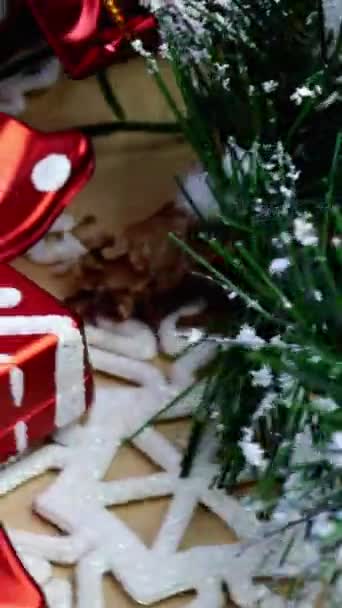 Decorações de Natal - ramos de abeto decorativos com bagas e cones, balas, presentes, flocos de neve giram no círculo no posto de madeira. Vídeo vertical. Fundo de Natal. — Vídeo de Stock