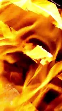 Parlak ateş ve alevler sıcak şöminede, kamp ateşinde ya da barbeküde yanar. Ateşin güzel dilleri ve kömürün sıcak parıltısı. Dikey video. Yakın plan. Dikey video.