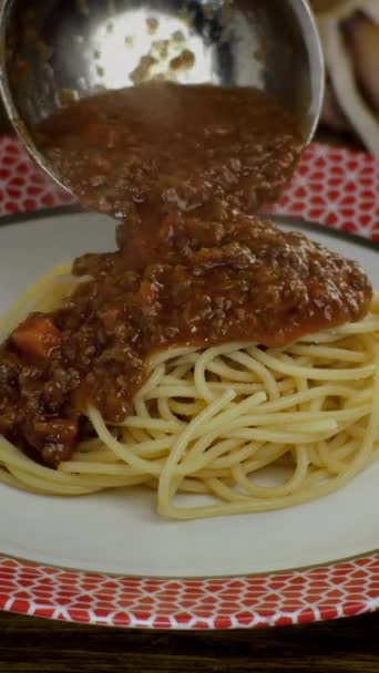 Bolognese σάλτσα βάζοντας σε μαγειρεμένα μακαρόνια ή tagliatelle ζυμαρικά σε λευκό πιάτο, σε εστιατόριο ή κουζίνα στο σπίτι. Πασπαλίζει παρμεζάνα. Σπιτική μαγειρική συνταγή. Κάθετη βίντεο. — Αρχείο Βίντεο