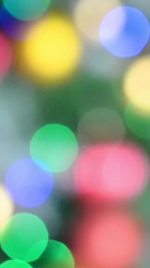 Bulanık renkli ışıklar. Kırmızı, yeşil, sarı, turuncu, mavi parıltılı ışıltılı şenlik arkaplanı. Soyut çok renkli ışık. Noel ya da parti konsepti. Dikey biçim.