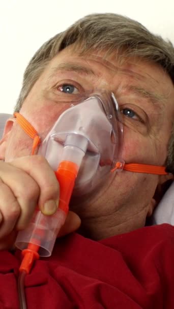 Kranker Mann mittleren Alters atmet im Bett durch eine Sauerstoffmaske. Behandlung von Asthma, Allergien, Bronchitis, Lungenentzündung bei Covid-19 und Atemwegserkrankungen. Vertikales Video. — Stockvideo