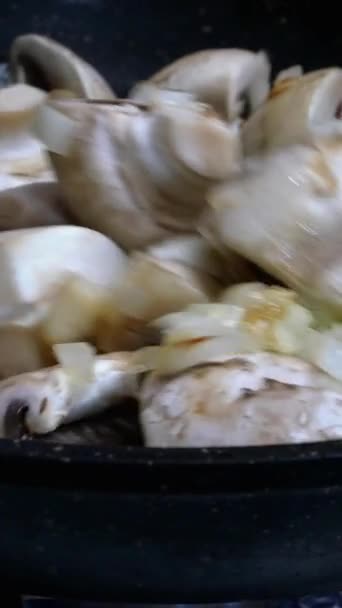 Bubur besar yang bisa dimakan champignons, dipotong menjadi empat irisan dan bawang cincang halus, mencampur dalam penggorengan panci untuk memasak dan membuat makanan lezat. Video Vertikal. Close-up. — Stok Video