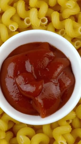 Un sacco di pasta secca come spirali e piattino con ketchup, ruotare cerchio. Popolare cucina italiana ed europea. Esperienza alimentare. Vista dall'alto. Cibo top down. Video verticale. — Video Stock