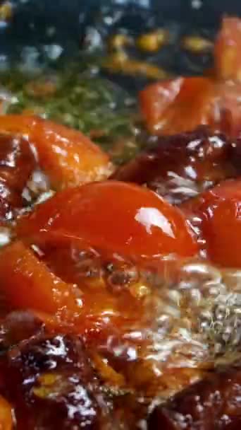 Deliciosas salchichas de caza grasosas, cortadas en trozos y en rodajas de tomate se fríen en sartén en aceite vegetal. Comida rápida y nutritiva. Cocina casera. Vídeo vertical. Primer plano. — Vídeos de Stock