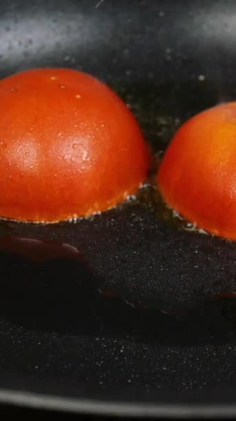 Tillaga stekta ägg med tomat i stekpanna till frukost på hushållsköket. Råa knäckta hönsägg faller i het skillet. Vertikal video. — Stockvideo