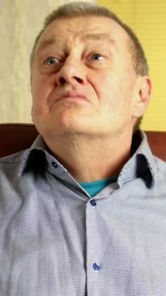Спящий взрослый мужчина кавказской национальности сидит в кожаном кресле в гостиной и кивает головой в согласии вверх и вниз. Вертикальное видео. — стоковое видео