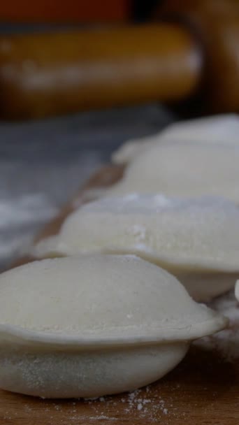 Rows of frozen raw pelmeni dumplings stuffed with mince meat on cutting board. Delicious traditional handmade food on domestic kitchen. Asian and russian cuisine. Vertical video. — Stock Video