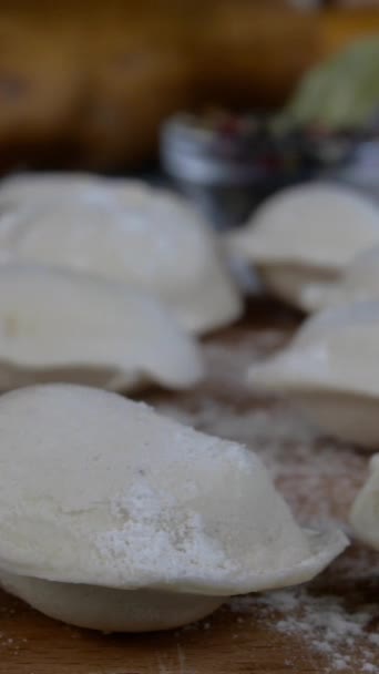 Σειρές κατεψυγμένων ωμών ζυμαρικών πελμένης με κιμά σε ξύλο κοπής. Νόστιμο παραδοσιακό χειροποίητο φαγητό στην οικιακή κουζίνα. Ασιατική και ρωσική κουζίνα. Κάθετη βίντεο. — Αρχείο Βίντεο