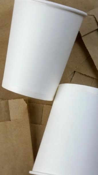 Pacote de papel vazio, embalagem biodegradável descartável ecológica para mercadorias e copo de papel vazio. Gira em círculo. Eco amigável fundo. Vídeo vertical. Vista superior. — Vídeo de Stock