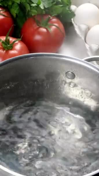 Шеф-повар кладет сухую пасту в кастрюлю с кипящей водой. Подготовка итальянской Tagliatelle в домашней кухне. Руки кладут макароны в кастрюлю. Вертикальное видео. Крупный план. — стоковое видео