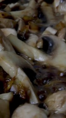 İnce doğranmış mantarlar haşlanmış sebze ya da zeytinyağında tavada kızartılır. Ev mutfağı. Dolly vurdu. Dikey video. Yakın plan..