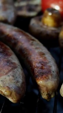 Izgarada ya da ızgarada pişirilmiş yağlı bavyera sosisi. Mantarlı ve domatesli. Dikey video. Yakın plan..