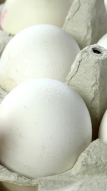 Los huevos de pollo blanco son frescos, apilados en envases de cartón ecológico y verduras frescas. Fondo alimenticio. Enfoque selectivo. Vídeo vertical. Primer plano. — Vídeos de Stock