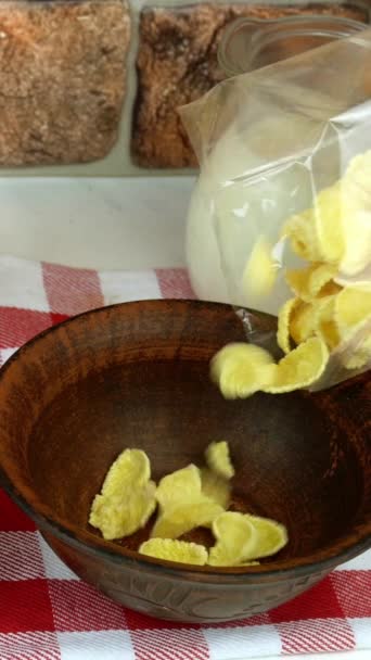 Verse natuurlijke melk wordt gegoten in een kom met cornflake van kruik, kooi servet. In de buurt zijn jam, sinaasappelsap en koekjes. Concept gezond ontbijtgranen. Verticale video. — Stockvideo