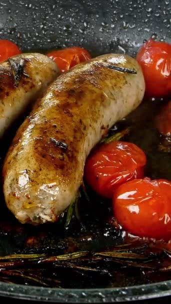 Vettige witte bavarische worsten met tomaat en takje rozemarijn worden gebakken in koekenpan op elektrisch fornuis. Engels of Duits, Europees of Amerikaans ontbijt. Verticale video. — Stockvideo