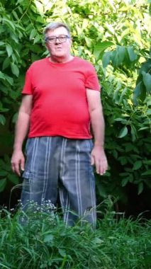 Günlük giysiler içinde kıdemli bir adam, belki emekli, arka bahçede ya da bahçede egzersiz ya da jimnastik yapıyor. Orta yaşlı insanlar için sağlıklı bir yaşam tarzı.