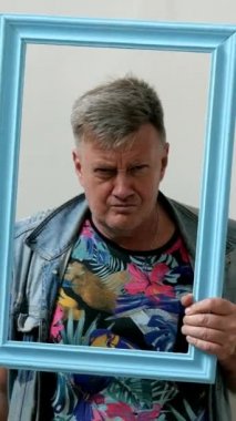 Portre çerçevesinden tuhaf bir son sınıf öğrencisi görünüşü, dili ve orta parmağı gösteriyor..