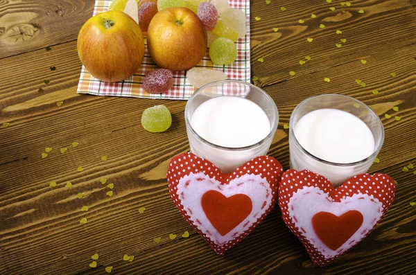 Dwa serca, jabłka na serwetce i dwie szklanki mleka. — Zdjęcie stockowe