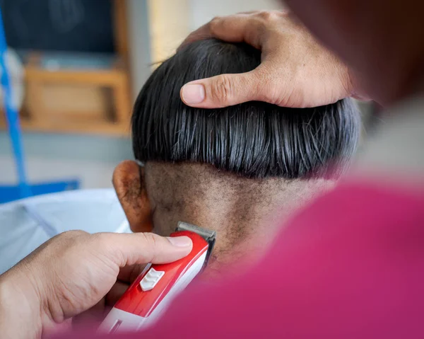 亚洲孩子在家里从父亲那里理发 小男孩用电动剃须刀救了他的头 — 图库照片