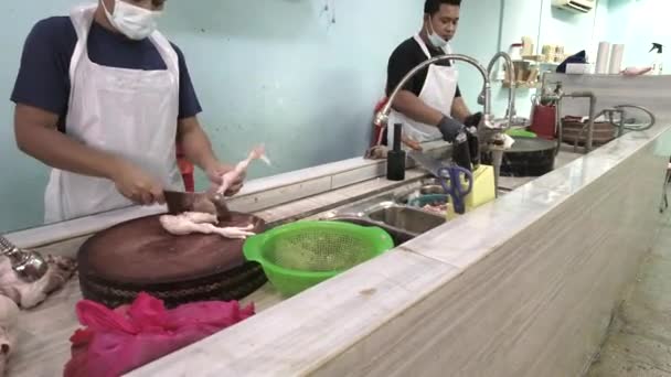 A munkás felvágja a csirkét a helyi boltban. A felvétel alacsony fényviszonyok miatt zajt tartalmazhat. — Stock videók