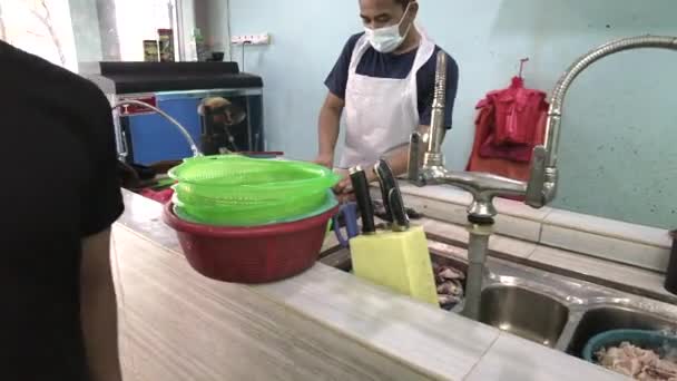 Oblast řezání ryb v místním obchodě s rybami. Dělníci jsou zaneprázdněni v pozadí. Záběry mohou obsahovat šum v důsledku slabého světla. — Stock video