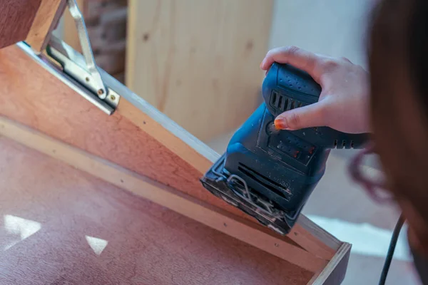 Hand sanding wood with a machine in the craftsman workshop.