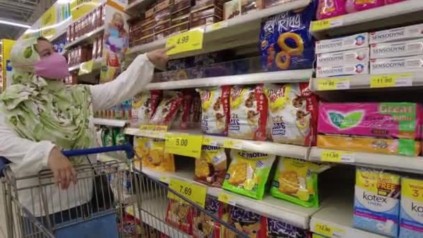 Bangi, Malaisie - Mars, 2021 Hijab femme musulmane en masque médical vérifier les prix de l'épicerie dans le supermarché Tesco. Ferme là. 4k — Video