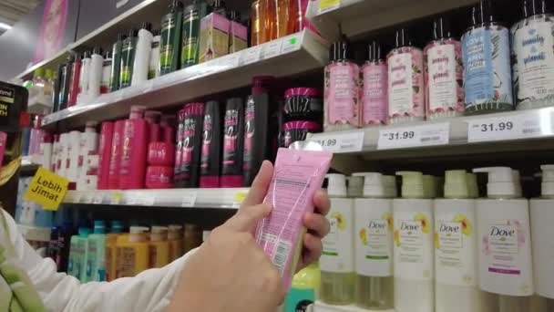 Bangi, Malaysia - März 2021 weibliche Kunden lesen Etikett auf Kosmetikflasche in Tesco Supermarkt. Aus nächster Nähe. 4k — Stockvideo